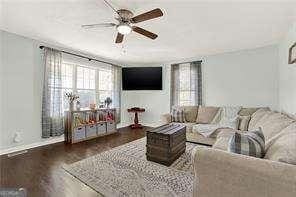 living room featuring ceiling fan and dark hardwood / wood-style flooring