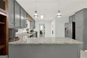 kitchen featuring decorative light fixtures, kitchen peninsula, and stainless steel refrigerator with ice dispenser