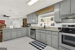 kitchen with appliances with stainless steel finishes, sink, gray cabinetry, and kitchen peninsula