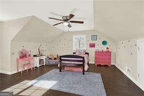 bedroom featuring dark wood-type flooring, vaulted ceiling, and ceiling fan