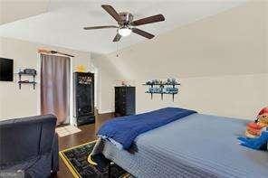 bedroom with wood-type flooring, ceiling fan, and vaulted ceiling