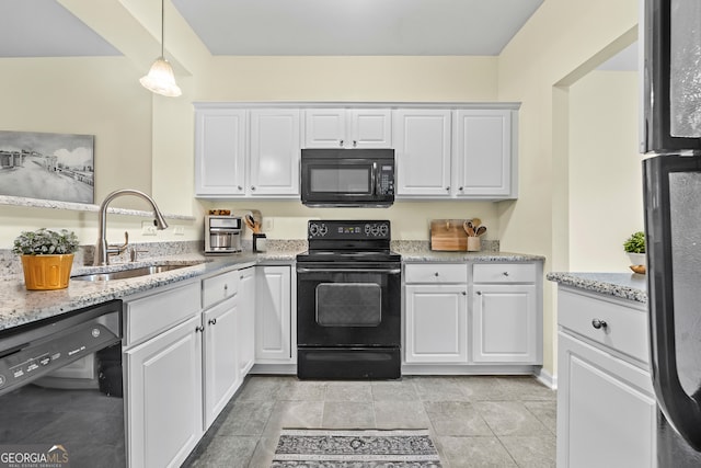 kitchen with light stone counters, a sink, white cabinetry, hanging light fixtures, and black appliances