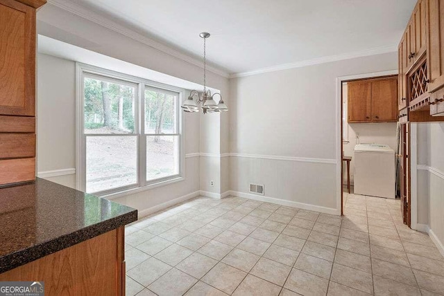 unfurnished dining area with a chandelier, ornamental molding, washer / dryer, and light tile patterned flooring