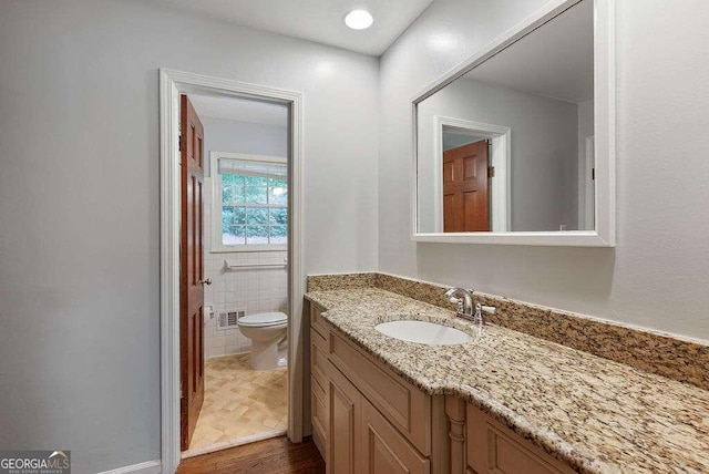 bathroom featuring vanity, tile walls, and toilet