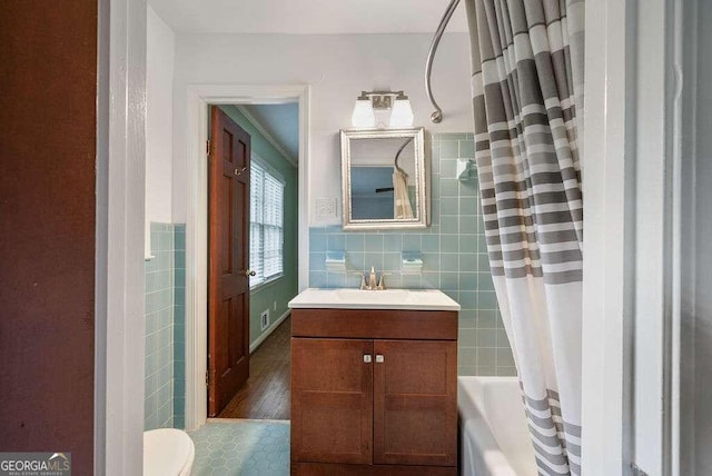 full bathroom with shower / bath combo, tile walls, vanity, and toilet