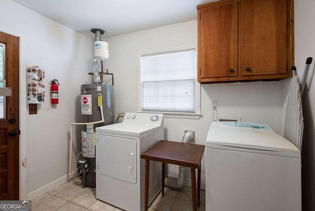 washroom featuring water heater, cabinets, light tile patterned floors, and washer and clothes dryer