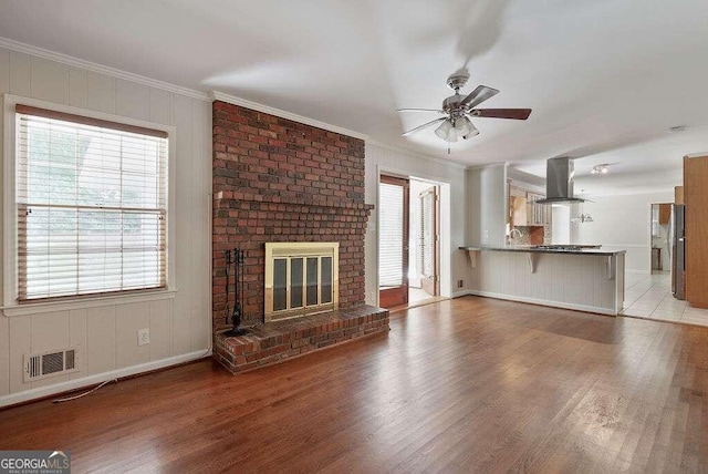 unfurnished living room featuring ornamental molding, a fireplace, and light hardwood / wood-style floors