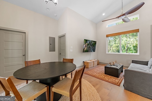 dining space with ceiling fan, wood-type flooring, electric panel, and high vaulted ceiling