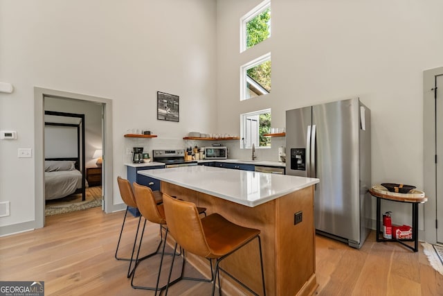 kitchen with a kitchen bar, a kitchen island, light hardwood / wood-style floors, and appliances with stainless steel finishes