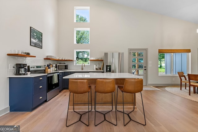 kitchen featuring a kitchen island, appliances with stainless steel finishes, a breakfast bar, and blue cabinetry