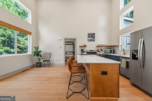 kitchen featuring appliances with stainless steel finishes, sink, a breakfast bar area, and a towering ceiling