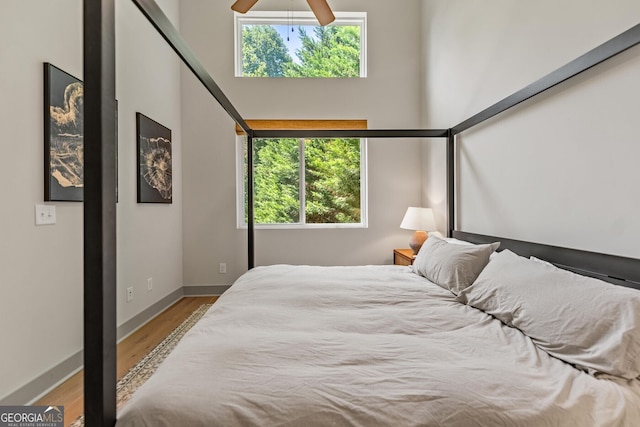 bedroom with a high ceiling, hardwood / wood-style floors, and ceiling fan