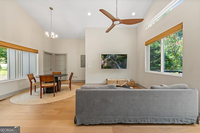 living room featuring high vaulted ceiling, ceiling fan with notable chandelier, electric panel, and light wood-type flooring