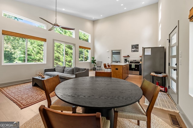 dining space featuring ceiling fan and a towering ceiling