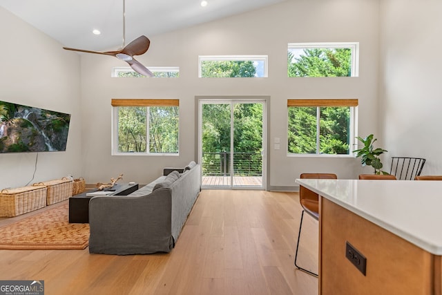 living room with plenty of natural light, high vaulted ceiling, and light hardwood / wood-style flooring