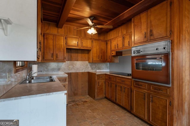 kitchen featuring sink, ceiling fan, wall oven, wooden ceiling, and beam ceiling