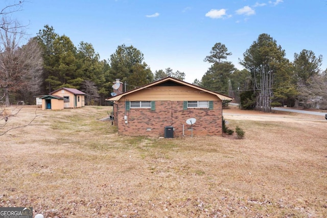 view of property exterior featuring a lawn, central air condition unit, and a shed