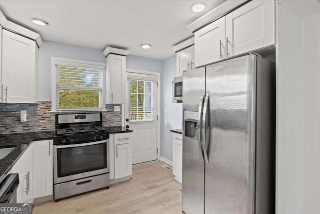 kitchen featuring white cabinetry, backsplash, light wood-type flooring, and appliances with stainless steel finishes