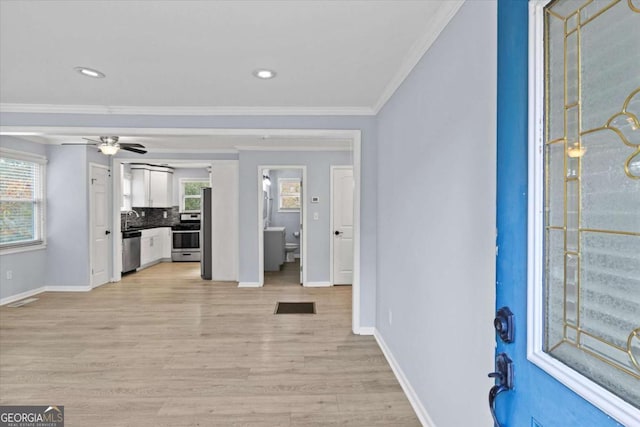 foyer with crown molding, a healthy amount of sunlight, ceiling fan, and light wood-type flooring