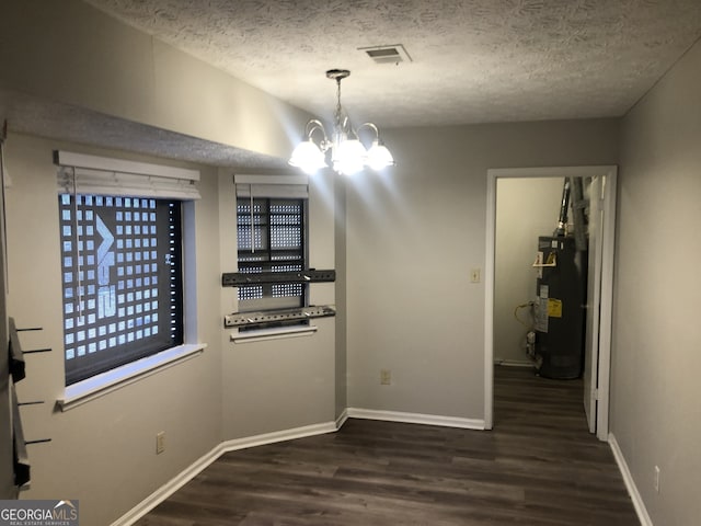 unfurnished dining area featuring an inviting chandelier, dark wood-type flooring, gas water heater, and a textured ceiling