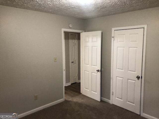 unfurnished bedroom featuring dark carpet and a textured ceiling