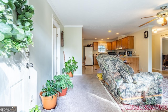 carpeted living room with crown molding and ceiling fan