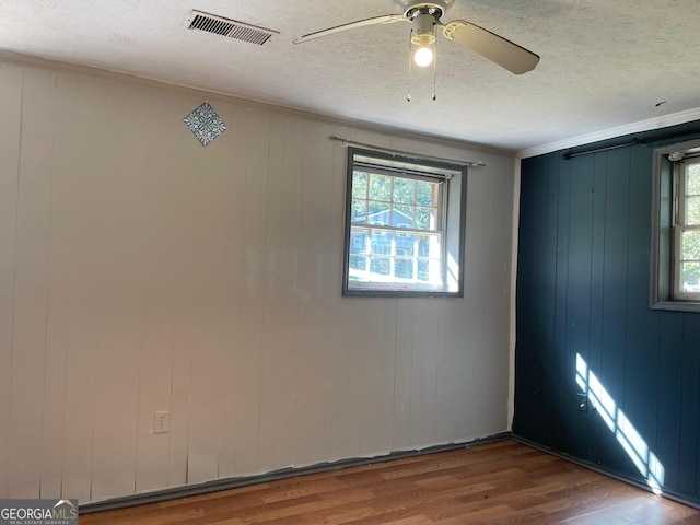 unfurnished room featuring ornamental molding, hardwood / wood-style floors, ceiling fan, and a textured ceiling