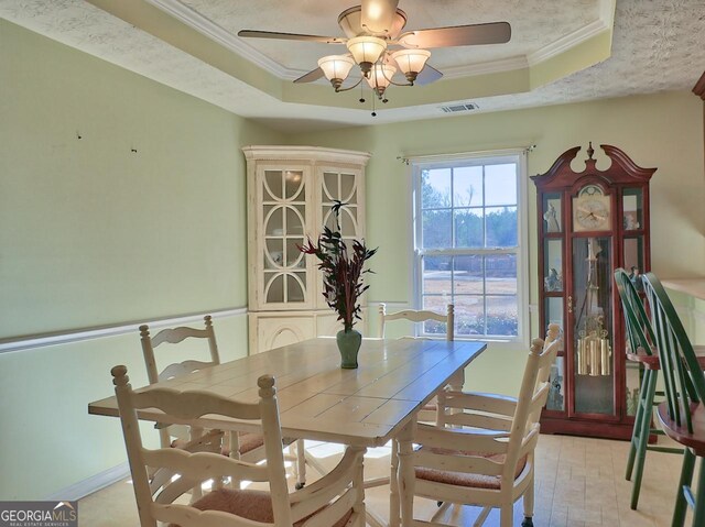 dining area with crown molding, ceiling fan, a raised ceiling, and a textured ceiling