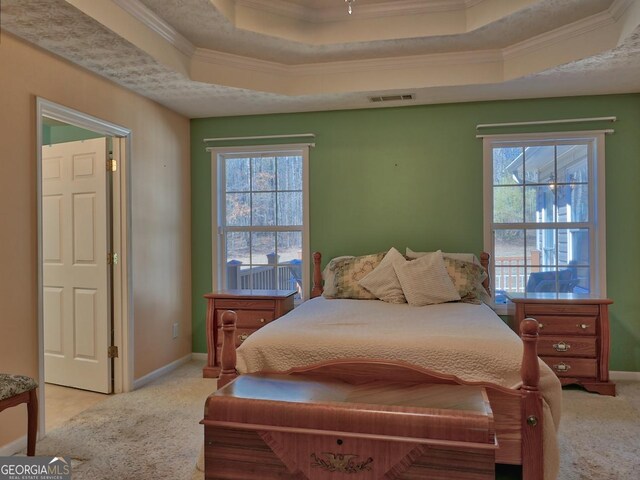 bedroom with crown molding, light colored carpet, and a tray ceiling