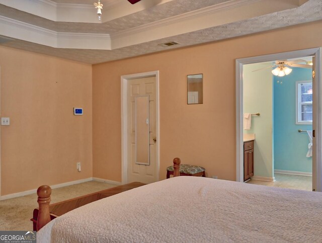 carpeted bedroom featuring crown molding, connected bathroom, and a tray ceiling