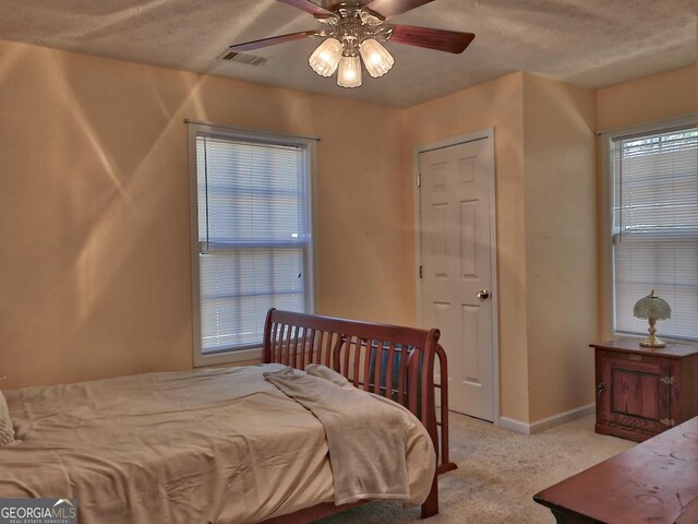 bedroom with light colored carpet, a textured ceiling, and ceiling fan