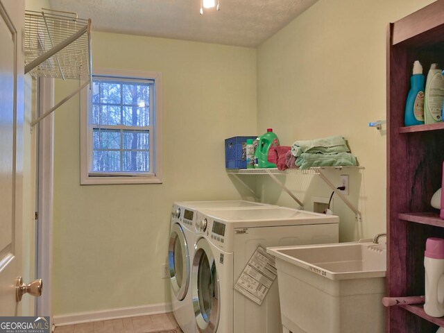 washroom featuring washing machine and dryer, sink, and a textured ceiling