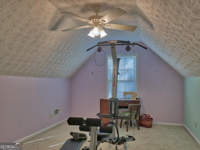 workout room with ceiling fan, carpet floors, vaulted ceiling, and a textured ceiling