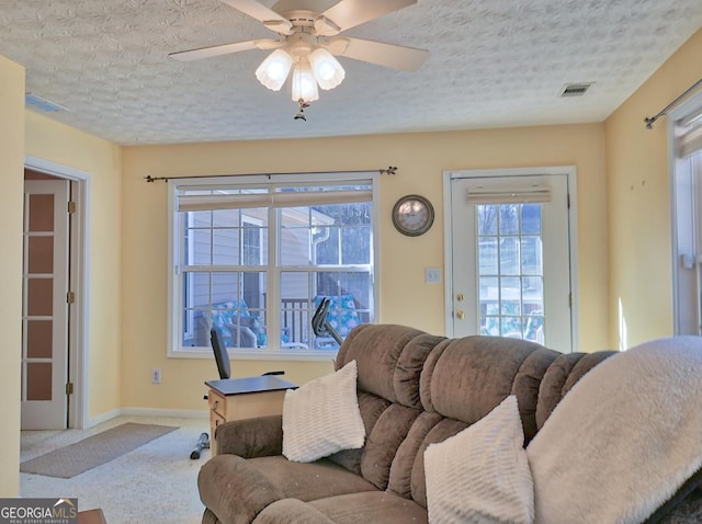 living room featuring ceiling fan, carpet, and a textured ceiling