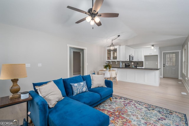 living room featuring lofted ceiling, sink, ceiling fan, and light hardwood / wood-style flooring