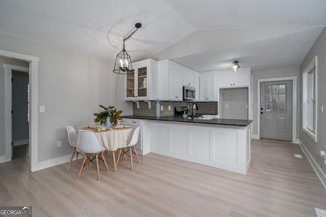 kitchen with lofted ceiling, sink, white cabinetry, tasteful backsplash, and pendant lighting