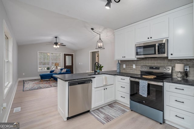 kitchen featuring lofted ceiling, stainless steel appliances, kitchen peninsula, and white cabinets