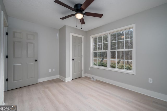 unfurnished bedroom featuring multiple windows, light hardwood / wood-style flooring, and ceiling fan