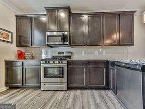 kitchen featuring dark brown cabinets, light hardwood / wood-style floors, and appliances with stainless steel finishes