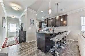 kitchen with plenty of natural light, dark brown cabinetry, ornamental molding, a kitchen bar, and kitchen peninsula