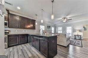 kitchen with sink, ornamental molding, dark brown cabinetry, ceiling fan, and light wood-type flooring