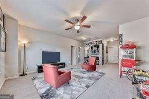 carpeted living room with ceiling fan