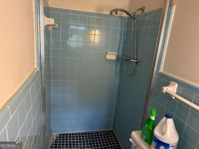 bathroom featuring tiled shower, toilet, and tile walls