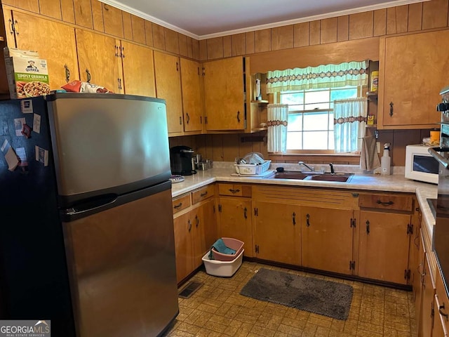 kitchen featuring ornamental molding, sink, and stainless steel fridge