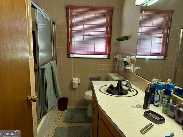 bathroom featuring vanity, tile patterned flooring, toilet, and tile walls