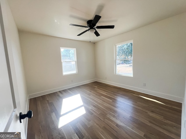 empty room featuring ceiling fan, plenty of natural light, and dark hardwood / wood-style floors