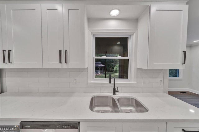 kitchen with light stone counters, sink, stainless steel dishwasher, and white cabinets