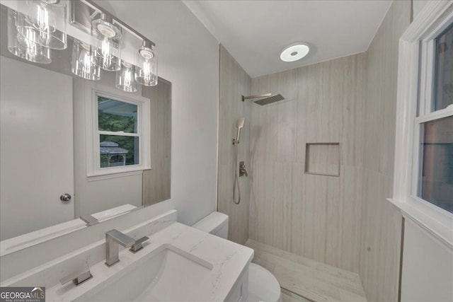 bathroom with tiled shower, vanity, and toilet