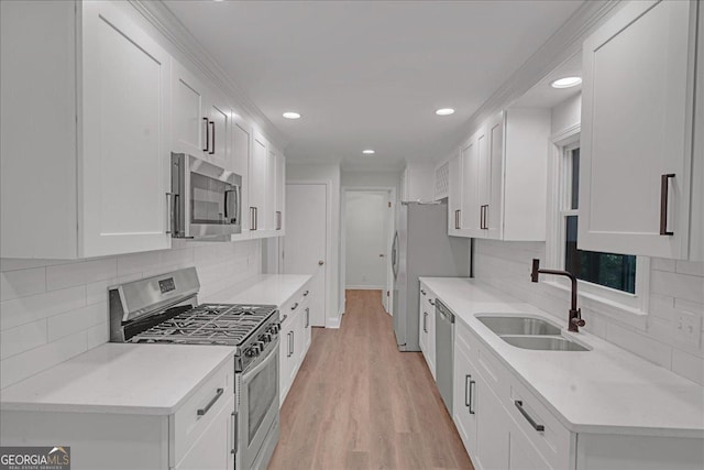 kitchen featuring sink, light wood-type flooring, appliances with stainless steel finishes, white cabinets, and backsplash