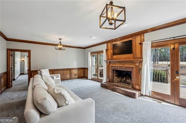 carpeted living room with crown molding, a chandelier, and a brick fireplace